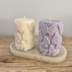 two candles sitting side by side on top of a wooden table next to each other