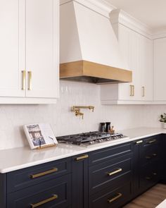 a kitchen with black and white cabinets, gold trimmings and an oven hood