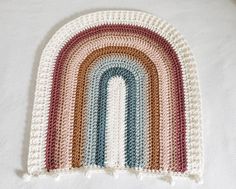 a crocheted rainbow rug is laying on a white surface, with the end cut off