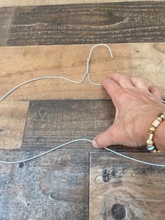 a person is making something out of yarn on the floor with their hand and string