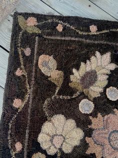 a brown rug with flowers on it sitting on a wooden floor next to a wall