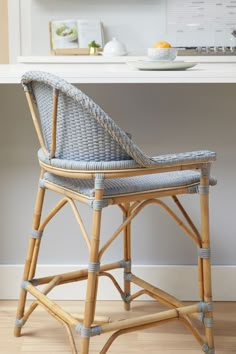 a wicker chair sitting in front of a counter with plates and bowls on it