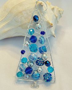 a glass christmas tree ornament sitting on top of a table next to a seashell