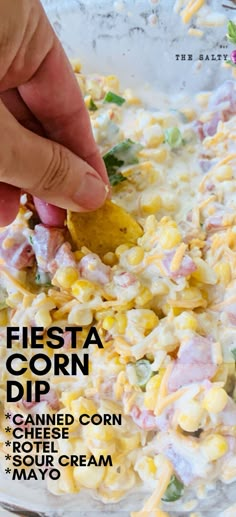 a person dipping a tortilla chip into a bowl of mexican corn salad with the title fiesta corn dip