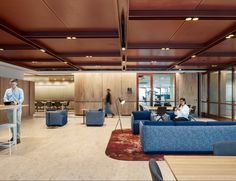 two people sitting on couches in a large room with wood paneling and exposed ceilings