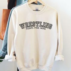 Show off your wrestling pride with our high-quality wrestling sweatshirts, perfect for athletes, fans, and parents alike. These sweatshirts are designed to keep you comfortable and warm, whether you're on the sidelines cheering at a tournament, supporting your team, or gearing up for practice.  Crafted for durability and style, our wrestling apparel is a must-have for anyone passionate about the sport. The bold designs and motivational themes make these sweatshirts ideal for showing your dedicat School Wrestling Shirts Ideas, Wrestling Designs For Shirts, Wrestling Shirts Ideas, Clothing Practice, Wrestling Apparel, High School Sport, Sideline Cheer