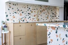 a kitchen with marble counter tops and wooden cabinetry, along with a gold faucet