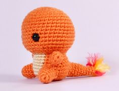 an orange crocheted stuffed animal holding a toy