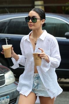 a woman walking down the street holding a drink