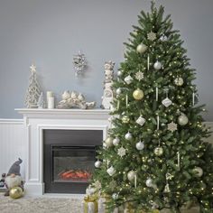 a decorated christmas tree in front of a fireplace with presents on the floor next to it