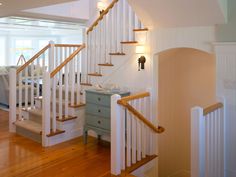 there is a staircase in the house with white railings and wood handrails