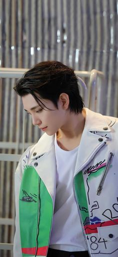 a man with black hair wearing a white shirt and green jacket