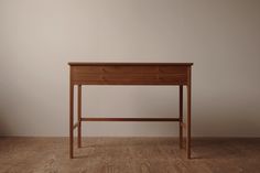 a small wooden desk with one drawer on the top and two drawers on the bottom