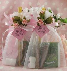 two bags filled with flowers and soaps on top of a pink table cloth covered in white polka dots