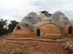 an unusual looking building on top of a dirt hill with trees in the back ground