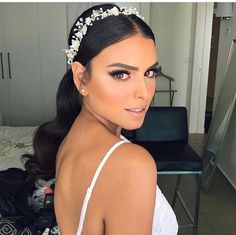 a woman in a white dress wearing a tiara with flowers on it's head