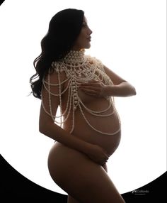 a pregnant woman with pearls on her back and breast, in front of a white circle