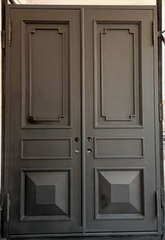 the double doors are painted gray and have glass inserts on each side, along with metal bars