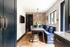 a dining room table and bench in front of a brick wall with wooden flooring