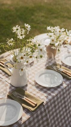 the table is set with plates, silverware and flowers in vases on it