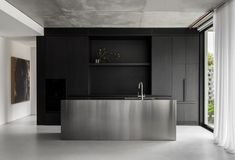 a modern kitchen with stainless steel counter tops and black cabinets, along with white curtains