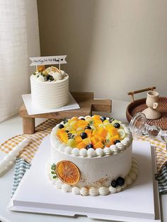 there is a cake with oranges and blueberries on the table next to it