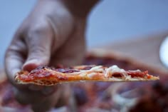 a person holding a slice of pizza in their left hand and reaching for it with both hands