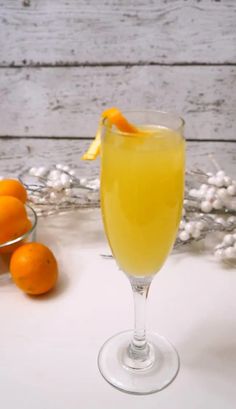 a glass filled with orange juice sitting on top of a table next to some fruit