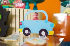 a blue toy car sitting on top of a table next to cupcakes and candy