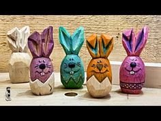 four painted wooden rabbits sitting next to each other on the floor in front of a wall