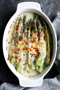 cheesy baked asparagus gratin in a white bowl with text overlay