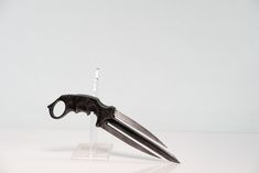 a pair of black scissors sitting on top of a clear display stand with the blades still attached