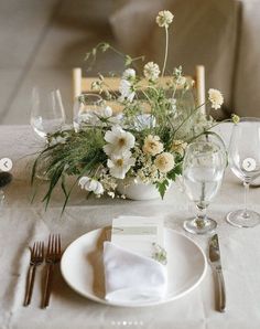 the table is set with white flowers and silverware