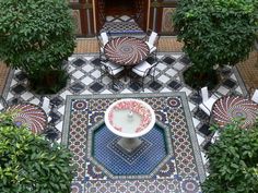 an aerial view of a patio with potted plants and tables in the center, surrounded by greenery