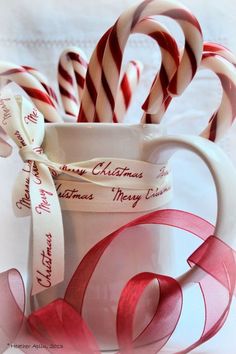 some candy canes are in a mug with ribbon around it and the words happy sunday