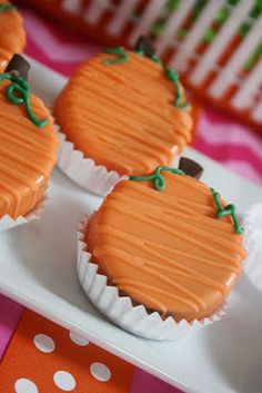 three cupcakes with orange frosting on a white plate and polka dot table cloth