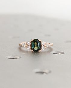 an oval green and white diamond ring on top of a table with drops of water