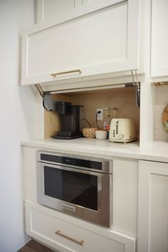 an oven built into the side of a white kitchen cabinet with gold handles and knobs