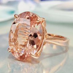 an oval shaped pink diamond ring sitting on top of a table