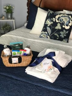 a bed with blue sheets, pillows and a basket filled with personal care items sitting on top of it