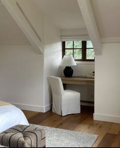 a bedroom with a bed, desk and chair next to a window in the corner