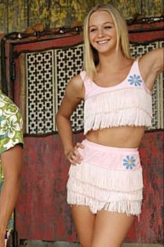 a woman in a pink outfit standing next to a man wearing a hawaiian shirt and shorts