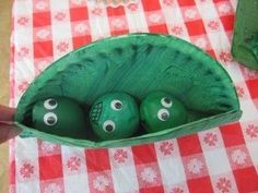 three green eggs with eyes in a paper bag on a checkered picnic tablecloth