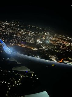 an aerial view of the city lights at night from inside an airplane window as it flies overhead