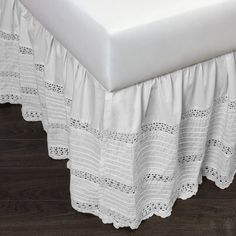 a white bed skirt on top of a wooden floor