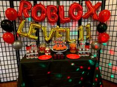 a table topped with balloons and cake next to a sign that says roblox