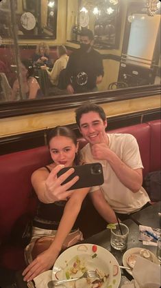 a man and woman taking a selfie in front of a mirror at a restaurant