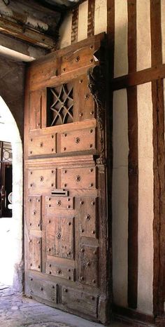 an old wooden door in the middle of a room with white walls and wood beams