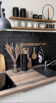 a kitchen with black tile and wooden counter tops is pictured in this image, there are various items on the shelves above the sink