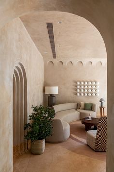 a living room filled with furniture next to a tall white wall covered in circles and arches